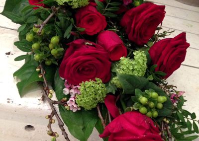 Begravningsbukett utifrån röda rosor och vackert grönt.